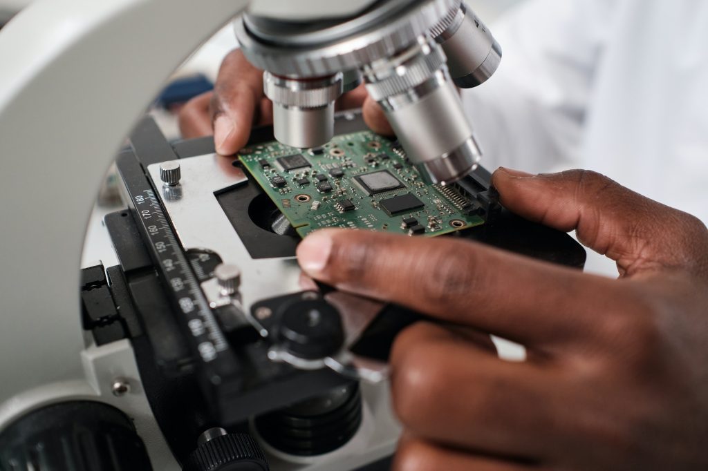 Part of hand of contemporary researcher putting circuit board in microscope